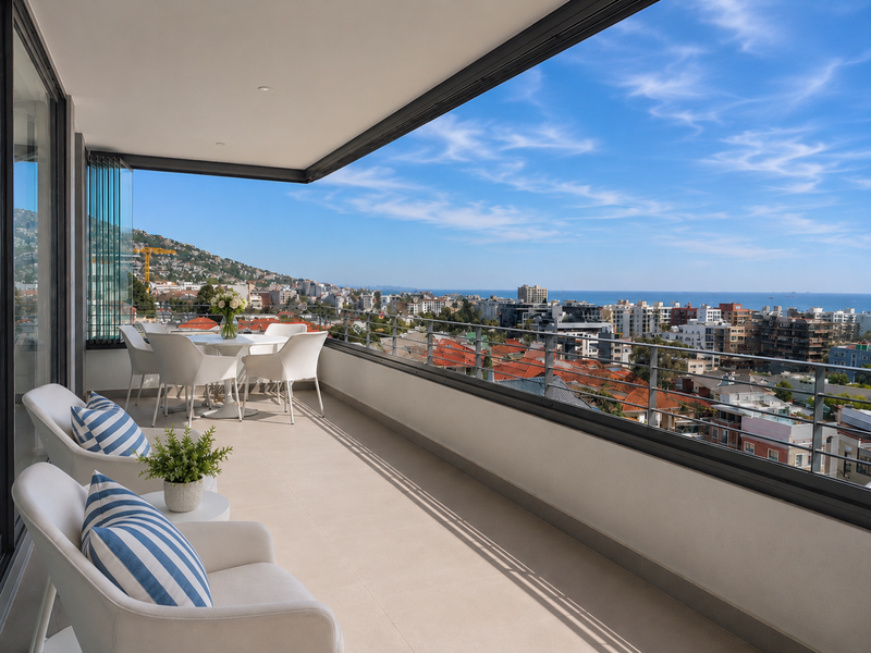 Spacious covered balcony featuring tiled flooring, glass balustrades, and panoramic city and ocean views.
