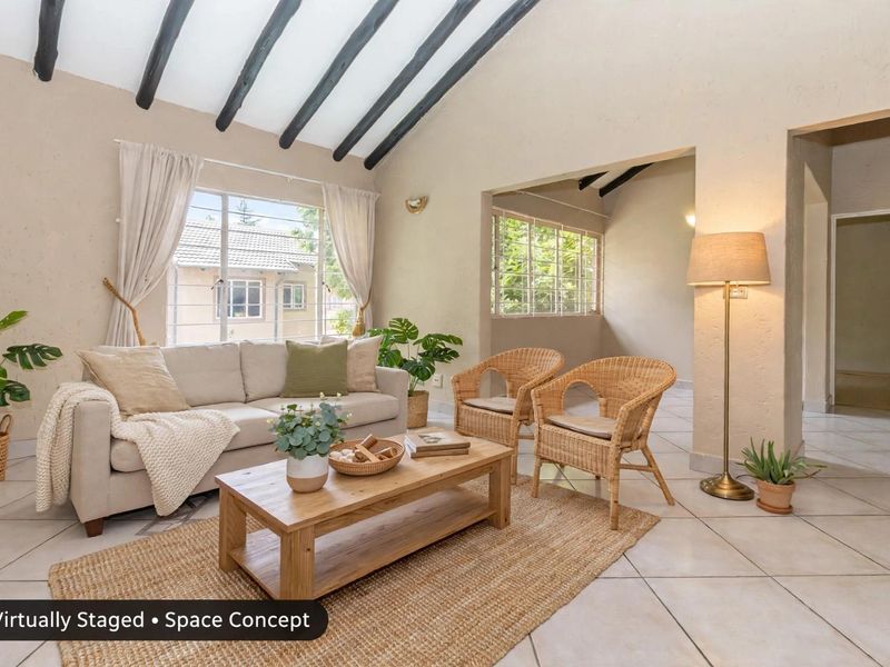 A bright living room featuring a vaulted ceiling with exposed timber beams, tiled flooring, and large windows with security bars.