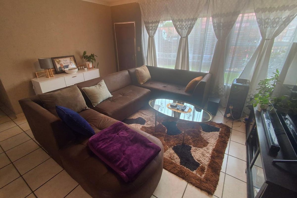 A comfortable living room featuring tiled flooring and large windows that allow for natural light.
