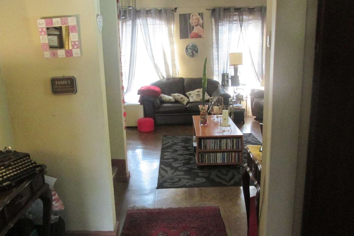 A view from the hallway looking into the living room, featuring tiled flooring and natural light from the windows.