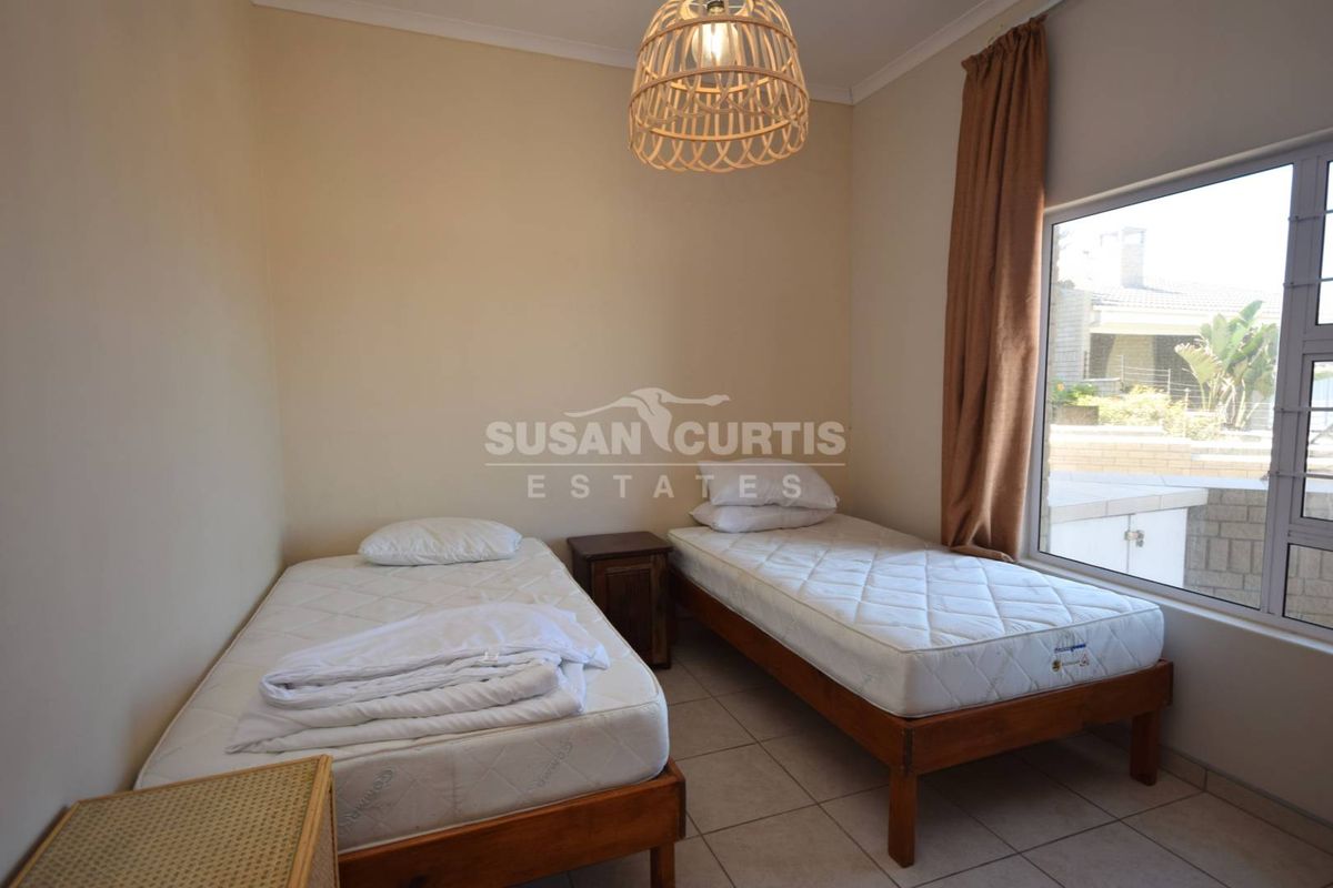 A functional bedroom featuring tiled flooring and a large window providing natural light.