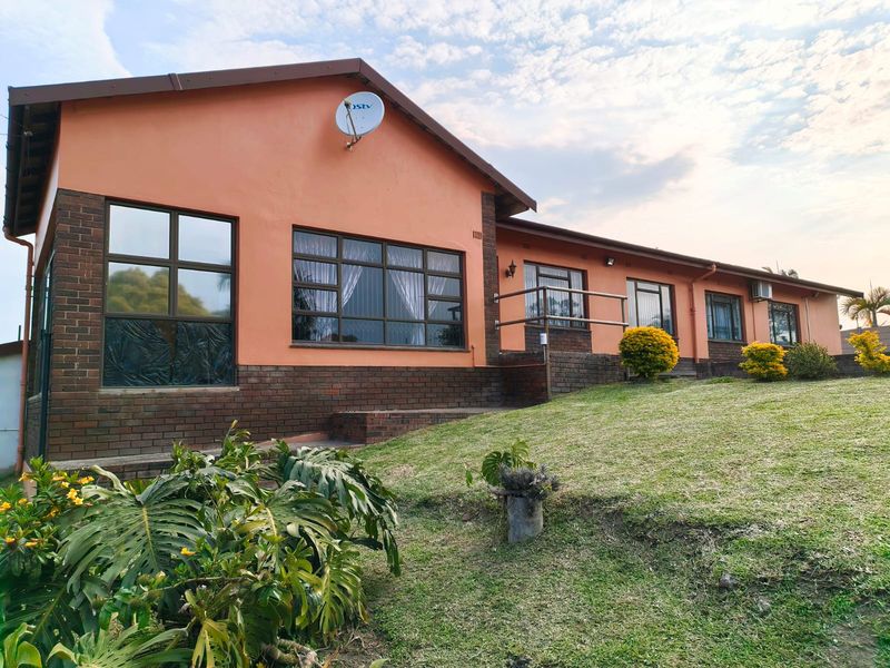 A single-story residential property featuring a combination of painted plaster and face-brick exterior walls with aluminium window frames and a sloped lawn.