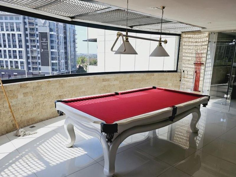 Spacious covered balcony featuring elegant travertine wall cladding, polished porcelain flooring, and a modern glass balustrade with expansive city views.