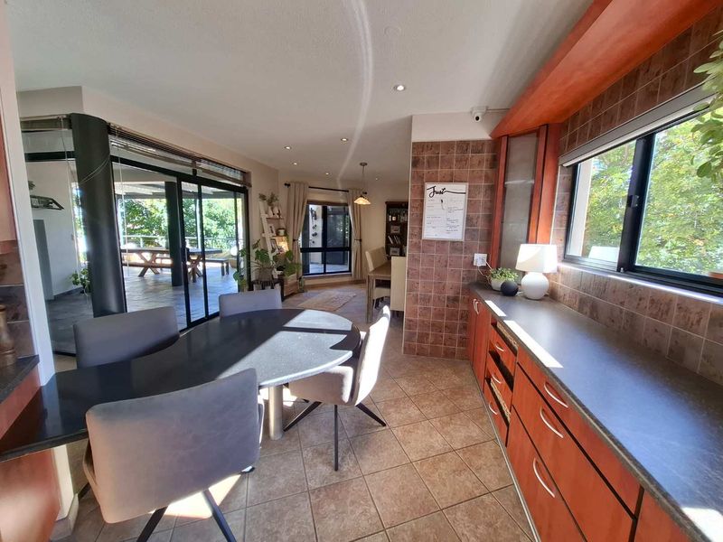 Open-plan living and dining area featuring tiled flooring, built-in cabinetry with laminate countertops, and large sliding glass doors leading to an outdoor patio.