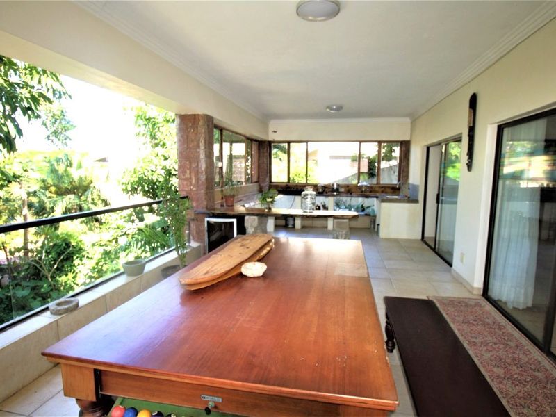 Spacious covered balcony featuring a built-in stone counter, glass balustrade, and sliding door access, ideal for outdoor entertaining and relaxation.