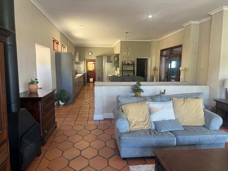 Spacious open-plan living and kitchen area featuring terracotta hexagonal floor tiles, a freestanding fireplace, and a functional kitchen layout with built-in cabinetry.