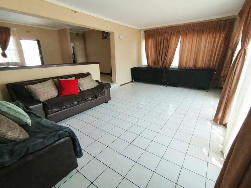Spacious open-plan living area featuring neutral tiled flooring and a semi-partitioned layout, offering a versatile space for lounge and dining arrangements.