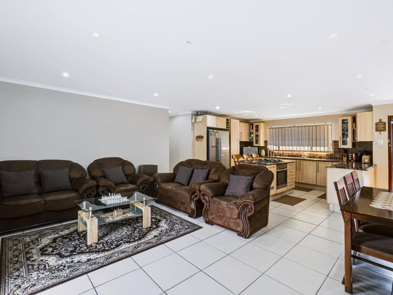 Open-plan living and dining area featuring tiled floors, recessed lighting, and a functional kitchen with built-in cabinetry and granite countertops.