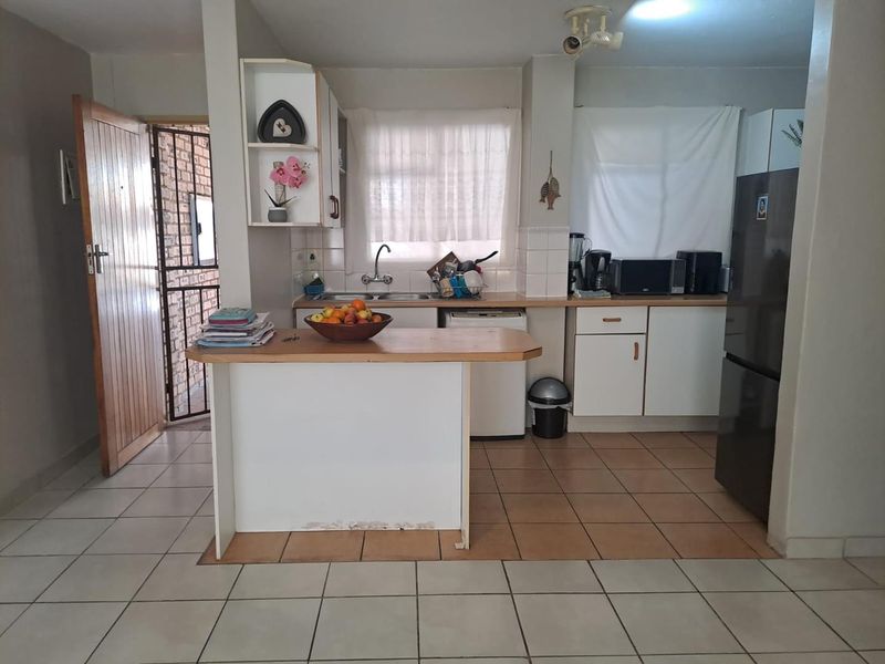 Functional kitchen featuring white cabinetry, laminate countertops, a breakfast bar, and tiled flooring, offering a practical layout for daily meal preparation.