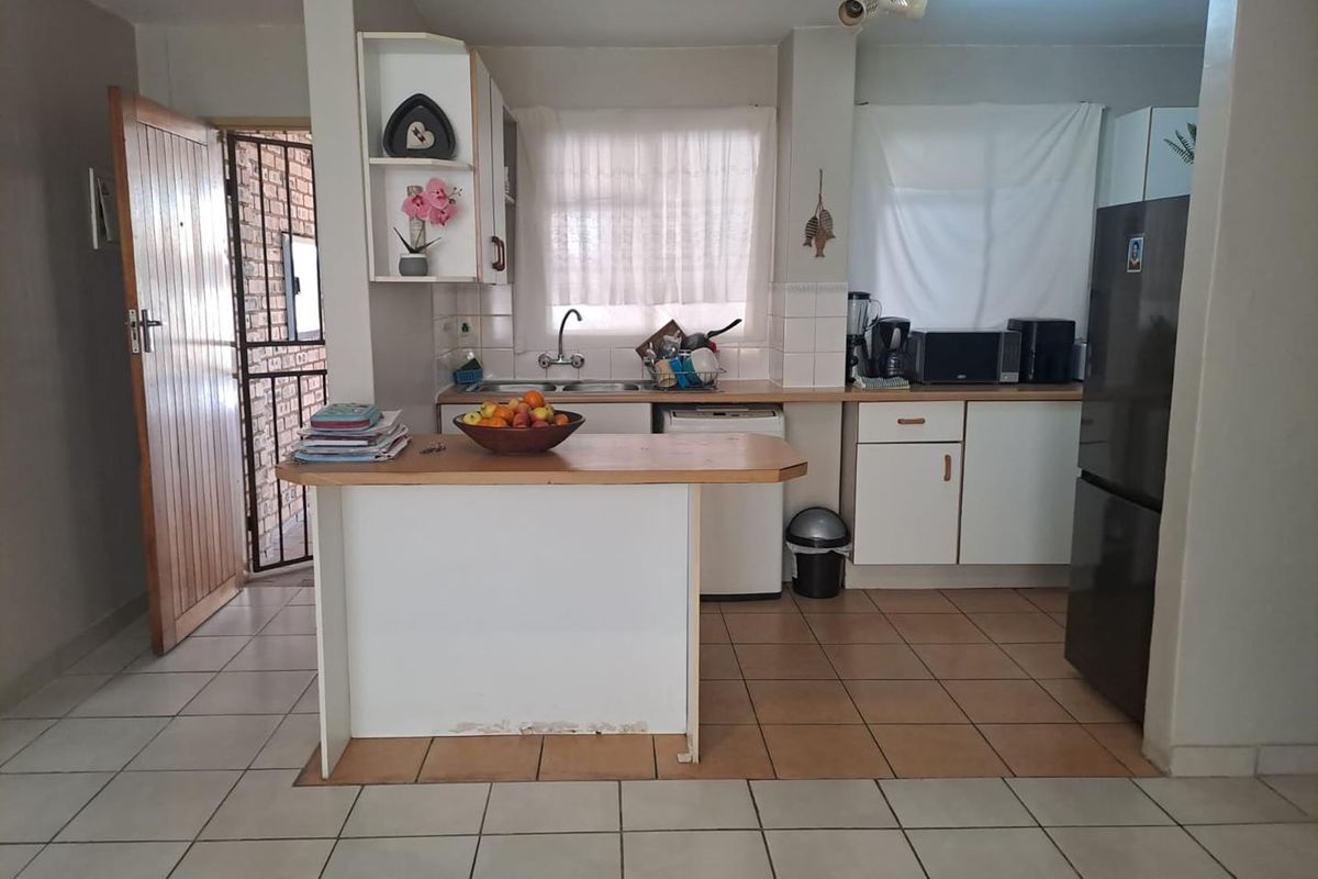 Functional kitchen featuring white cabinetry, laminate countertops, a breakfast bar, and tiled flooring, offering a practical layout for daily meal preparation.