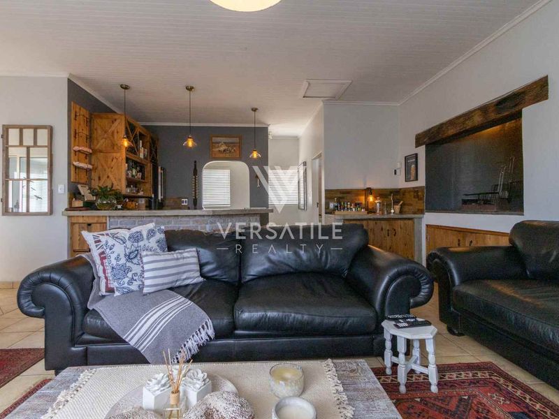 Open plan living area featuring a built-in bar with stone cladding, timber shelving, and a rustic timber ceiling finish.