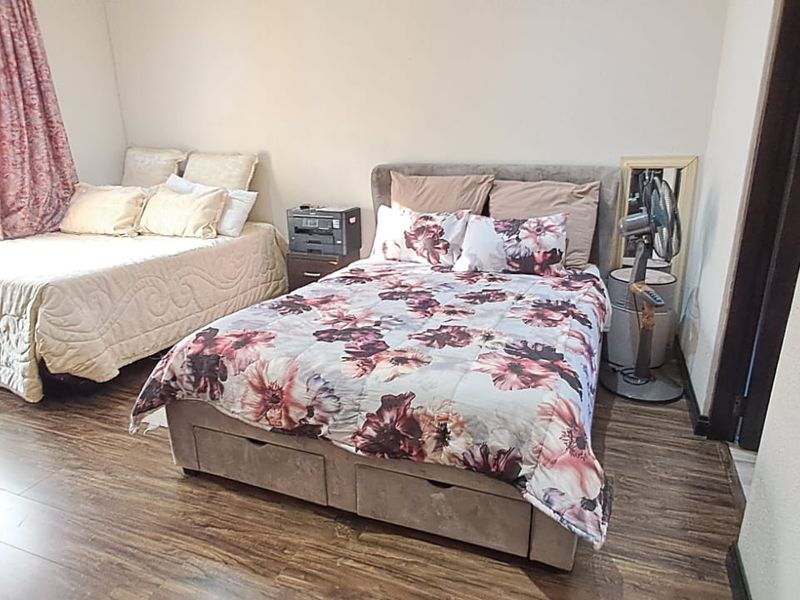 A bedroom featuring laminate flooring and neutral wall finishes, providing a functional space with natural light.