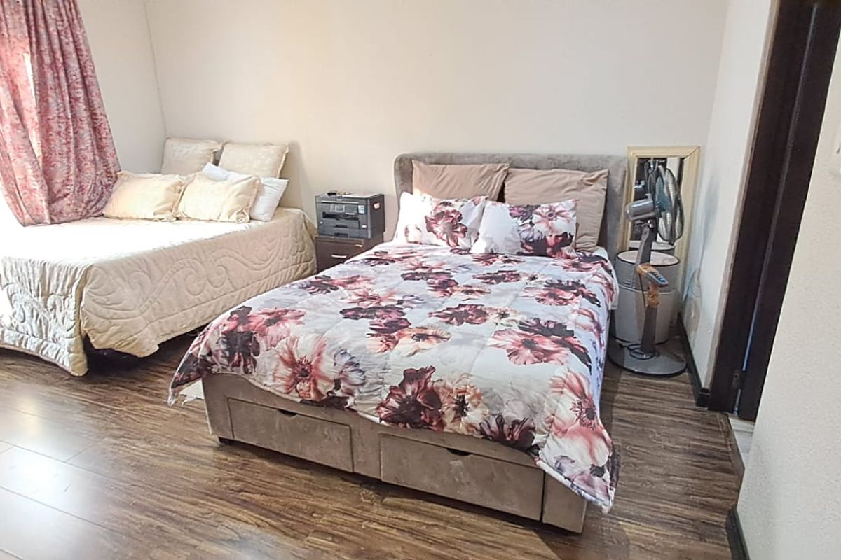 A bedroom featuring laminate flooring and neutral wall finishes, providing a functional space with natural light.