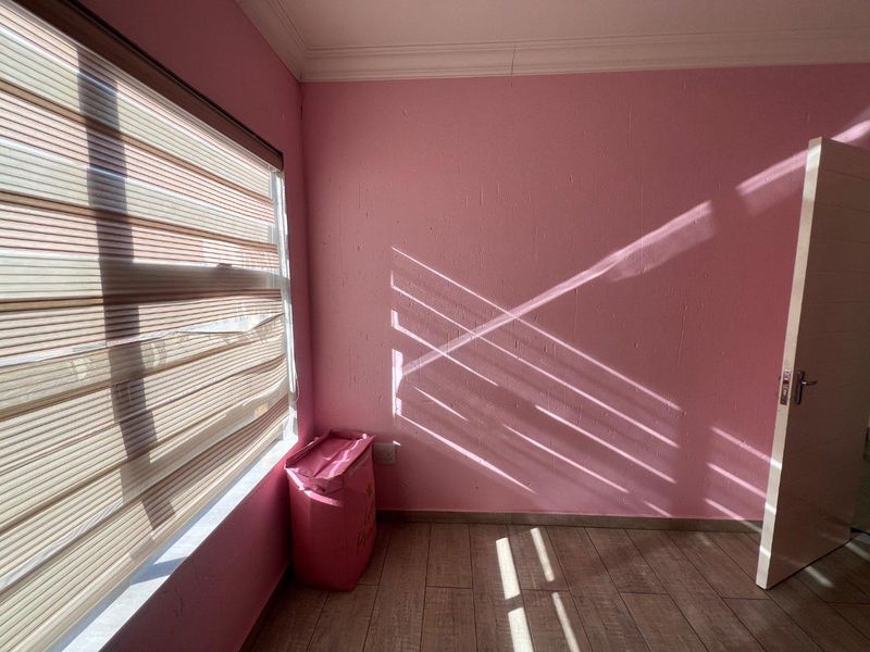 A bright, empty bedroom featuring tiled flooring, coving, and roller blinds, offering a blank canvas for personalization.