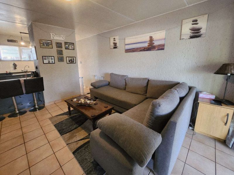 Open-plan living area featuring tiled flooring and a breakfast bar connecting to the kitchen space.