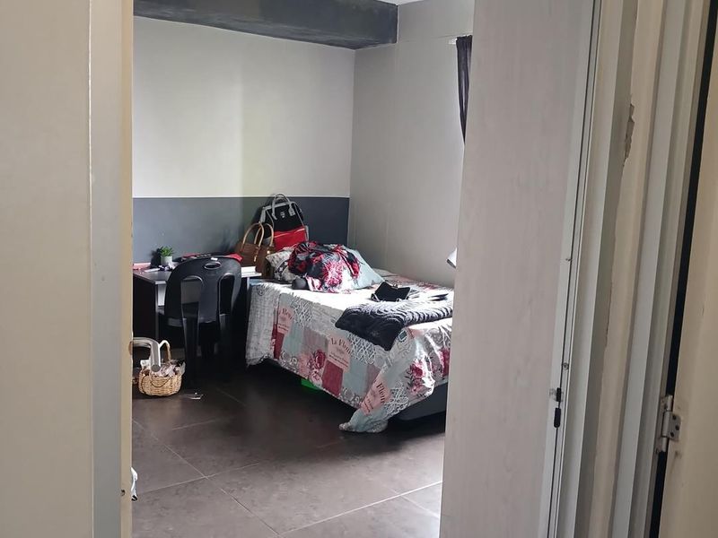 A bedroom featuring dark tiled flooring and a two-tone wall finish with an exposed ceiling beam, viewed from the doorway.