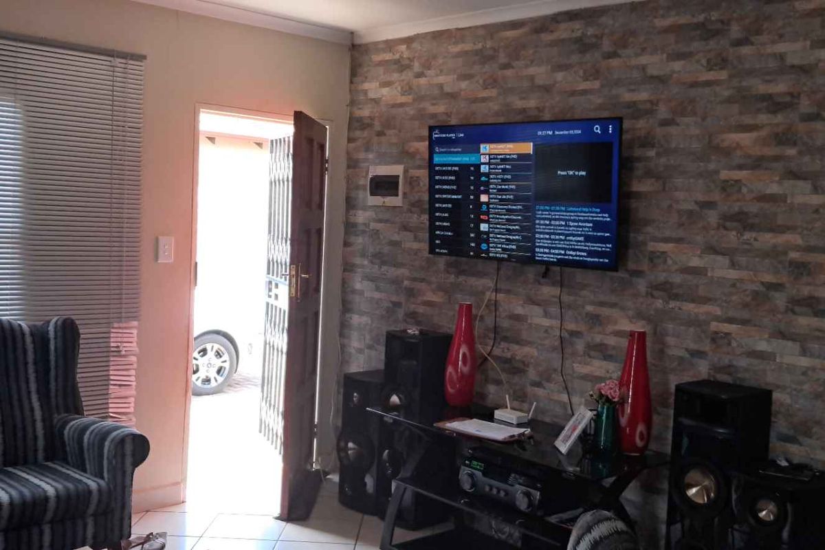 Living room featuring a stone-cladding feature wall, tiled flooring, and a door leading to the exterior.