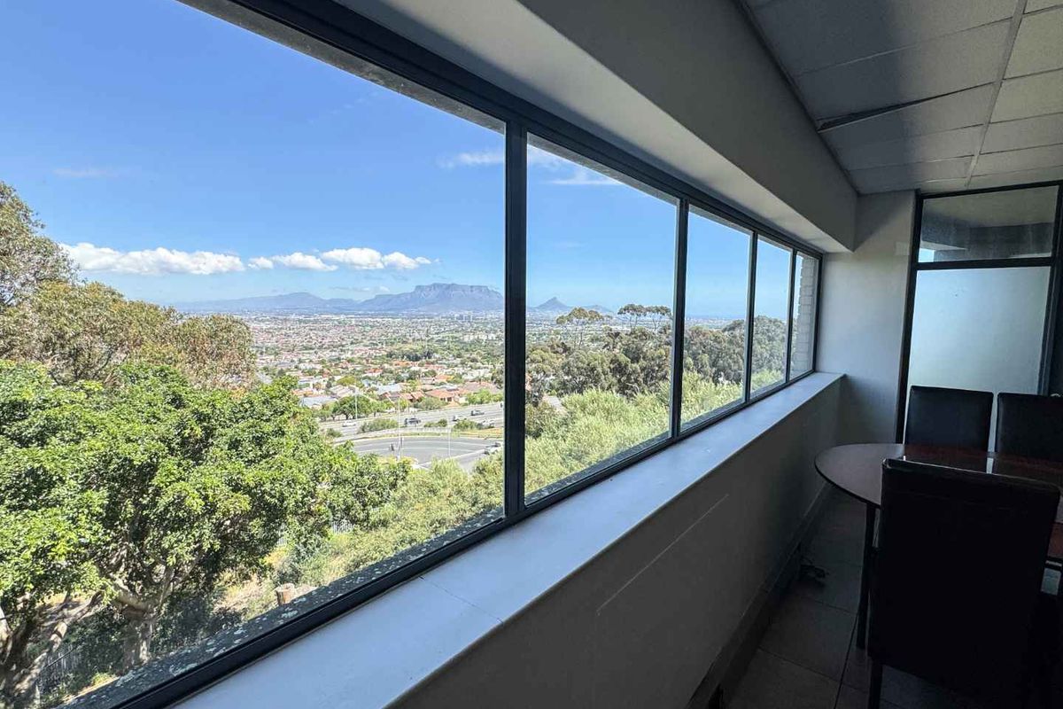 An interior office space featuring expansive panoramic windows that offer a clear, elevated view of the surrounding landscape and distant mountains.
