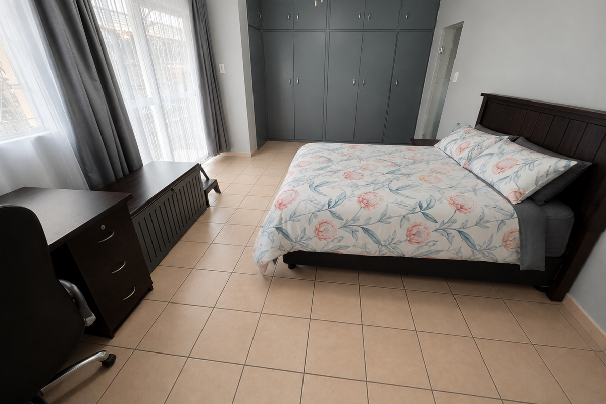 A well-maintained bedroom featuring built-in floor-to-ceiling cabinetry, tiled flooring, and large windows with curtains, providing a clean and functional living space.