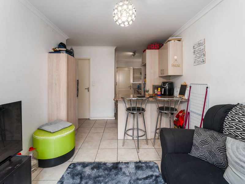 Open plan living area featuring tiled flooring and a compact kitchen with breakfast bar and built-in cabinetry.
