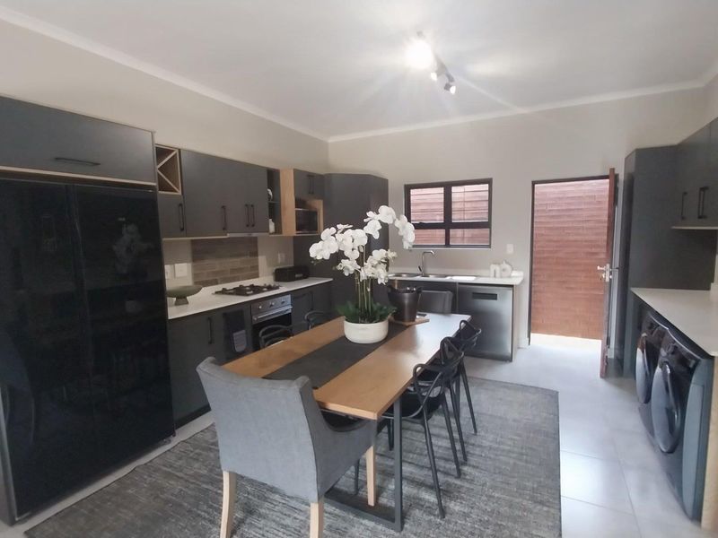 Modern kitchen featuring dark cabinetry, stone countertops, integrated appliances, and direct access to an outdoor area, offering a sleek and functional culinary space.