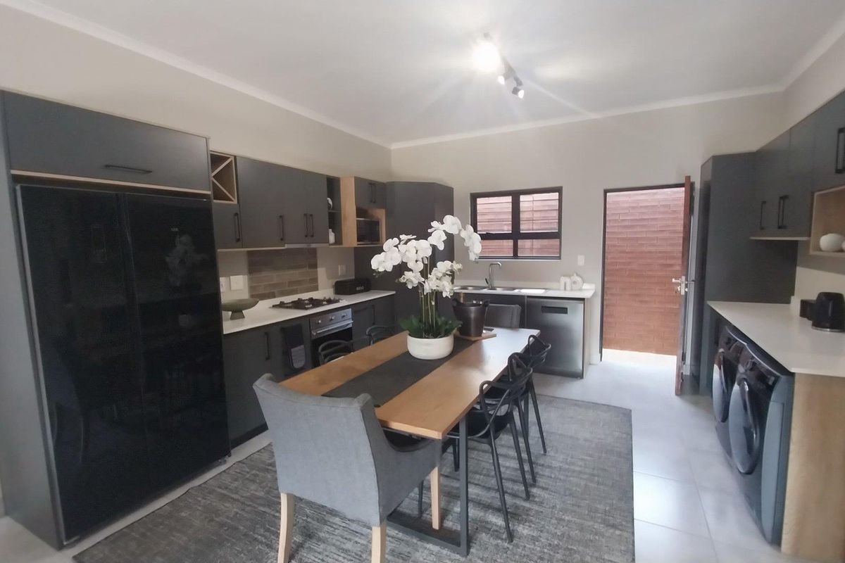 Modern kitchen featuring dark cabinetry, stone countertops, integrated appliances, and direct access to an outdoor area, offering a sleek and functional culinary space.