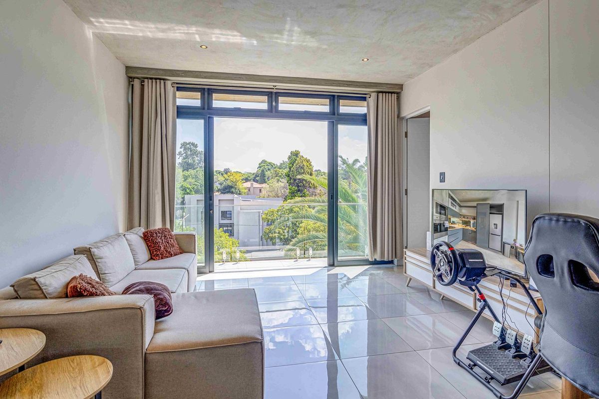 Modern living room featuring large sliding glass doors that open onto a balcony, providing ample natural light and views of the surrounding area.