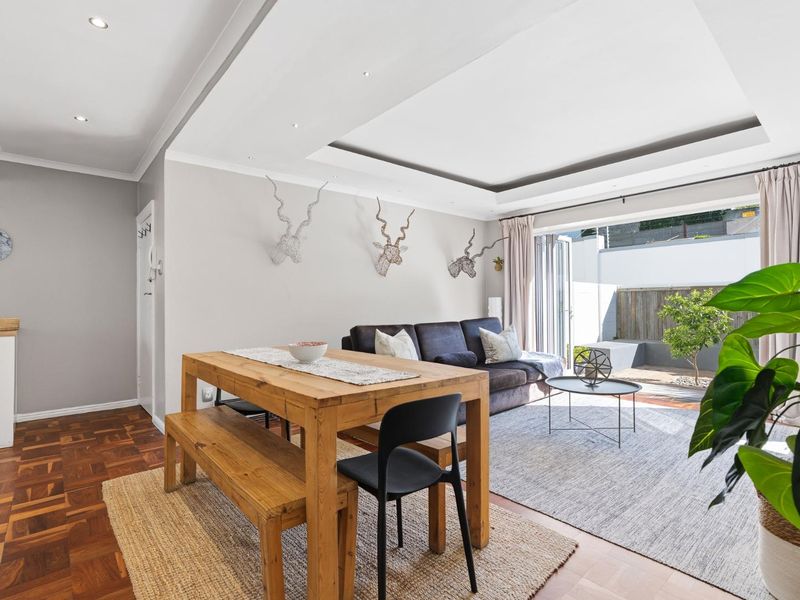 Bright open-plan living and dining area featuring elegant parquet flooring, recessed ceiling lighting, and seamless access to the outdoor patio through bi-fold doors.