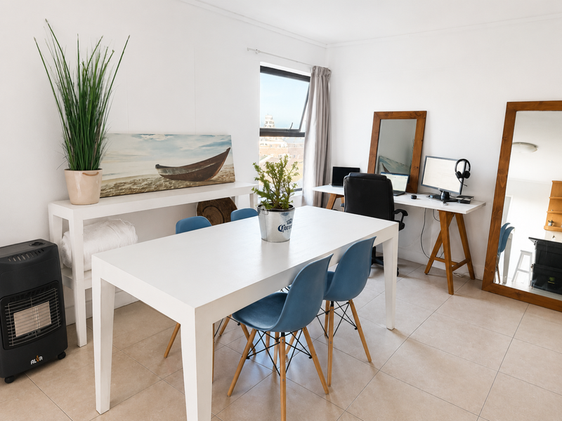 A bright, open-plan living area featuring neutral tiled flooring and a large window providing natural light and an exterior view.