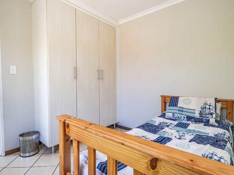 A functional bedroom featuring light-toned built-in wardrobes and tiled flooring, offering a clean and neutral space for personalization.