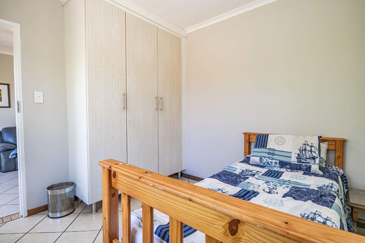 A functional bedroom featuring light-toned built-in wardrobes and tiled flooring, offering a clean and neutral space for personalization.