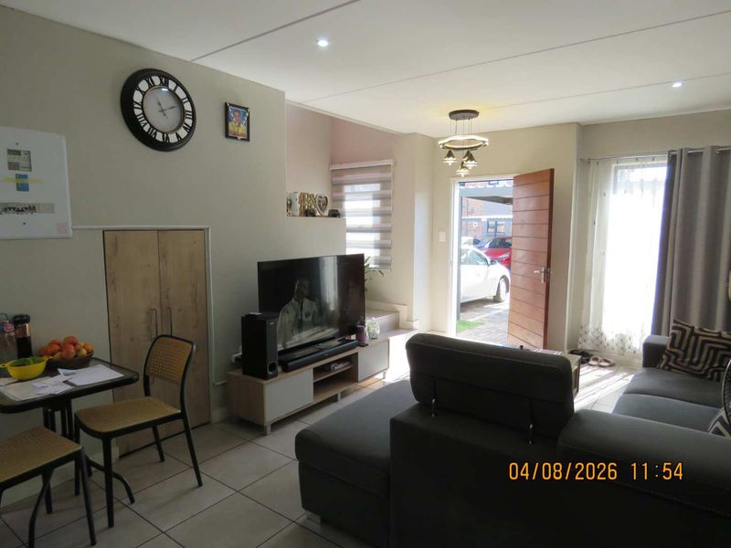 Open-plan living area featuring tiled flooring, recessed lighting, and a built-in storage cupboard, with direct access to the exterior entrance.
