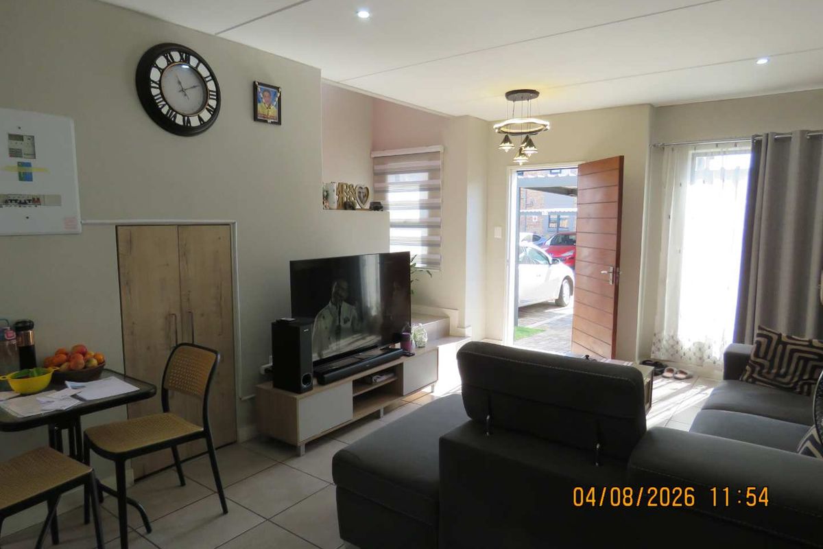Open-plan living area featuring tiled flooring, recessed lighting, and a built-in storage cupboard, with direct access to the exterior entrance.