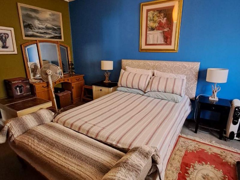A bedroom featuring bold blue and green accent walls, providing a functional space with standard lighting and layout.
