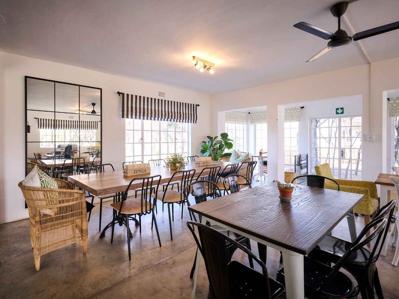 Spacious open-plan living and dining area featuring polished concrete floors, large windows, and ceiling fans, offering a bright and airy atmosphere.