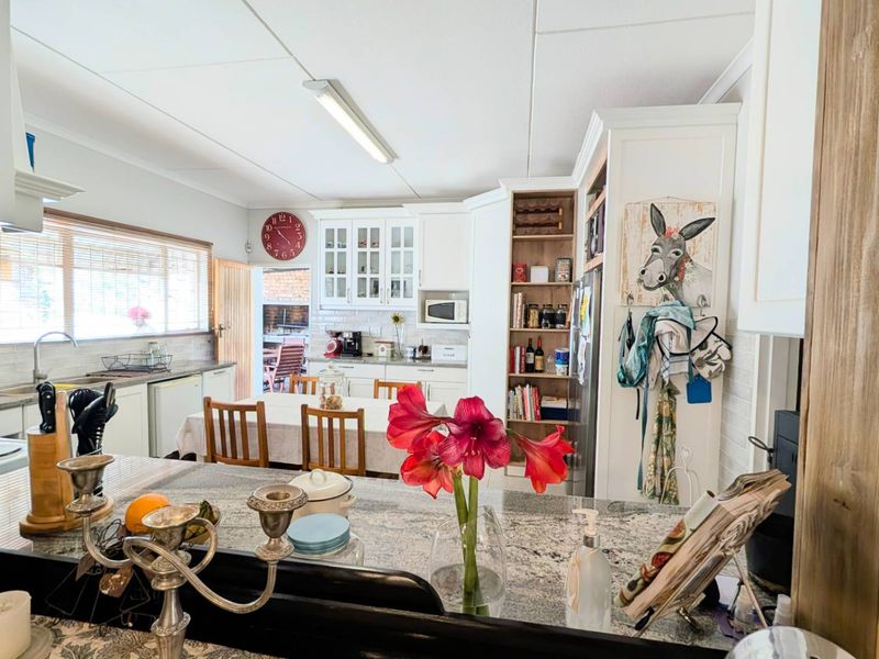 A functional kitchen featuring granite countertops, ample built-in cabinetry, glass-front display units, and integrated shelving, offering a practical layout for daily use.