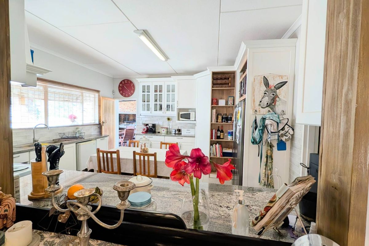 A functional kitchen featuring granite countertops, ample built-in cabinetry, glass-front display units, and integrated shelving, offering a practical layout for daily use.