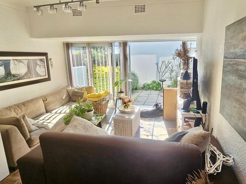 A living room featuring textured walls, track lighting, and large sliding glass doors that provide direct access to a paved outdoor patio area.