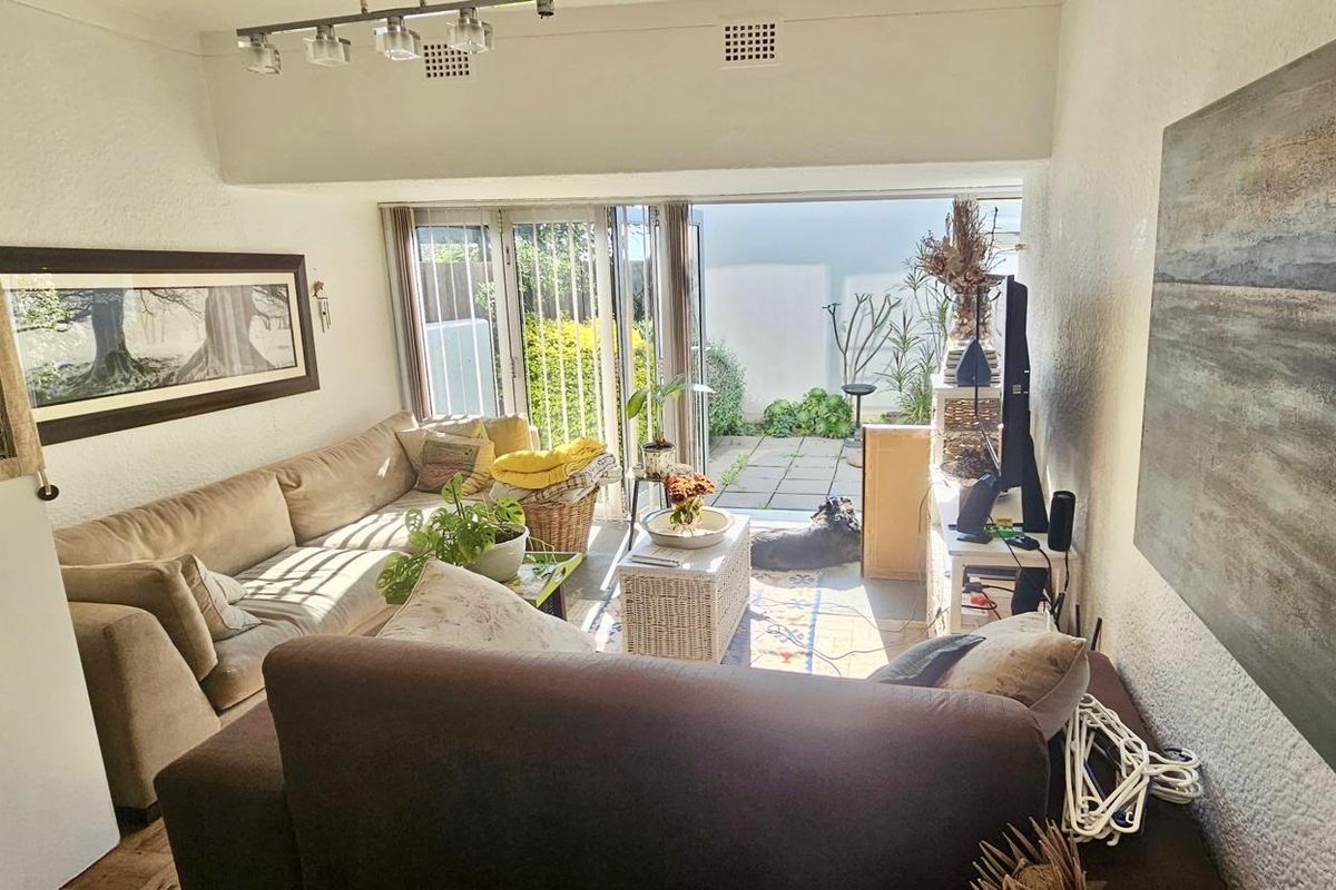 A living room featuring textured walls, track lighting, and large sliding glass doors that provide direct access to a paved outdoor patio area.