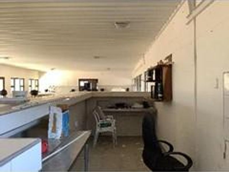 An open-plan interior space featuring a corrugated metal ceiling and built-in shelving, currently used as a functional workspace.