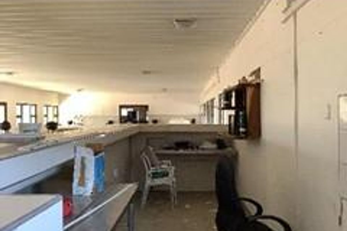 An open-plan interior space featuring a corrugated metal ceiling and built-in shelving, currently used as a functional workspace.