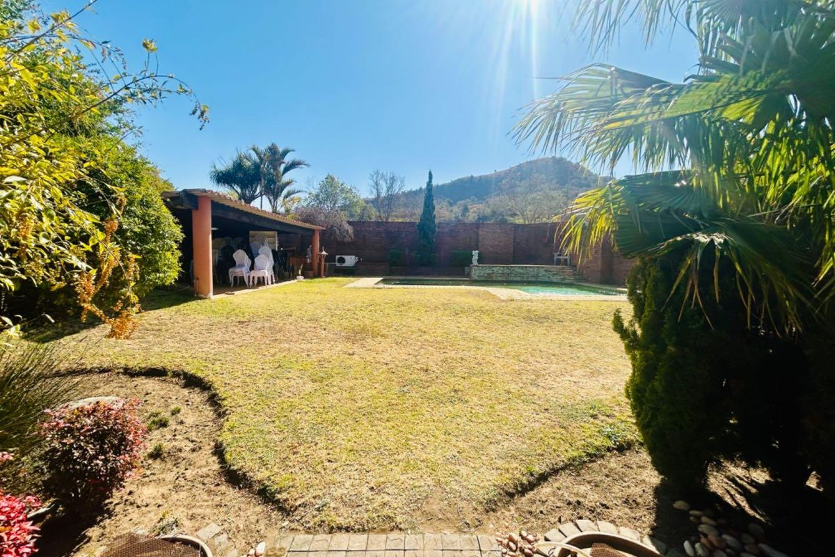 Spacious rear garden featuring a swimming pool, covered patio area, and established landscaping with mountain views.