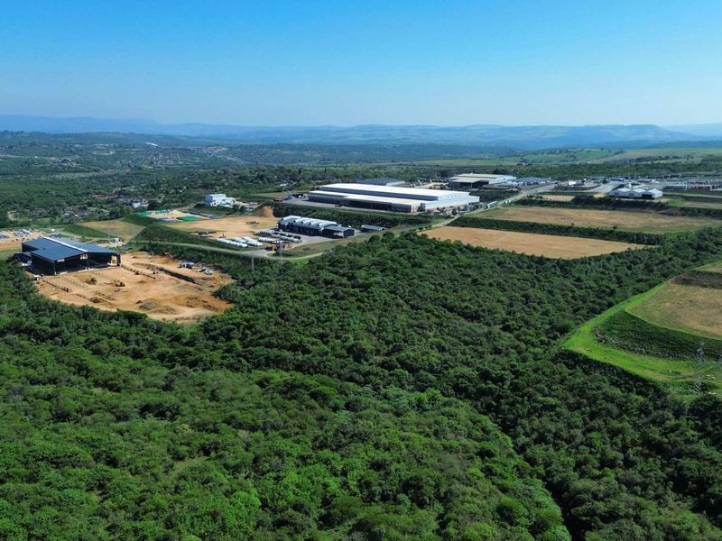 Aerial view of an industrial park featuring large warehouse facilities, paved access roads, and surrounding undeveloped land with natural vegetation.