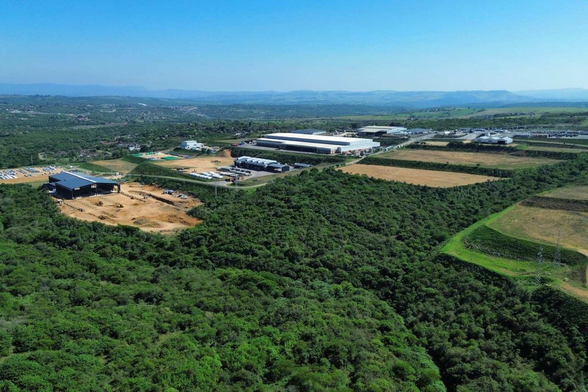 Aerial view of an industrial park featuring large warehouse facilities, paved access roads, and surrounding undeveloped land with natural vegetation.
