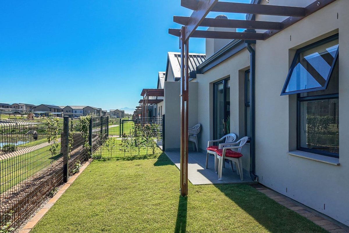 A well-maintained rear patio area featuring a timber pergola, paved flooring, and a private garden overlooking the retirement village grounds.