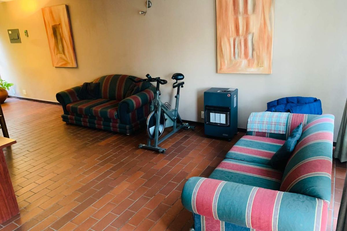 A living area featuring terracotta tile flooring and a built-in gas heater, offering a functional space with potential for modern updates.
