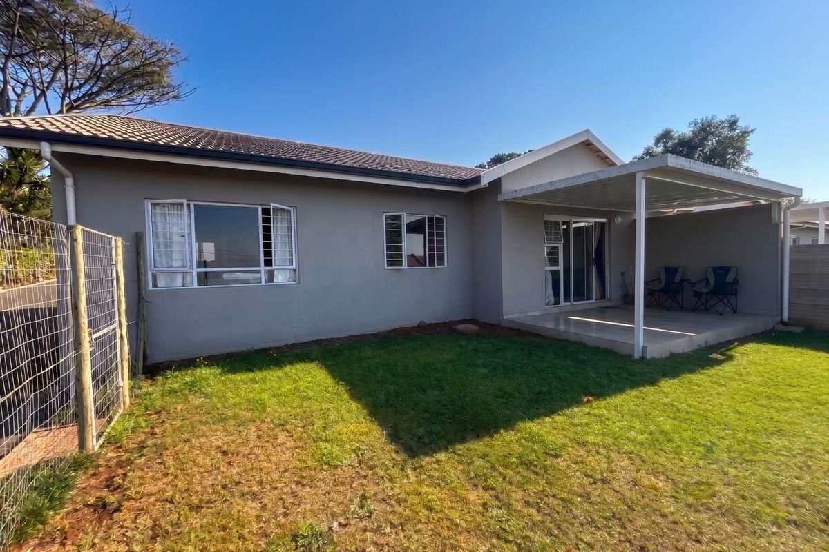 Rear view of the townhouse featuring a covered patio, sliding glass doors, and a private garden area with wire mesh fencing.