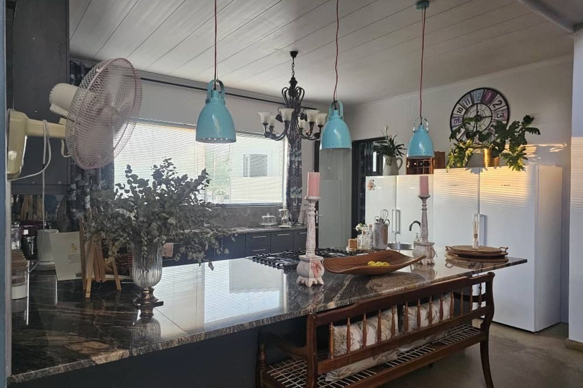 Spacious kitchen featuring a large granite-topped island with integrated gas hob, complemented by stylish pendant lighting and ample built-in cabinetry.