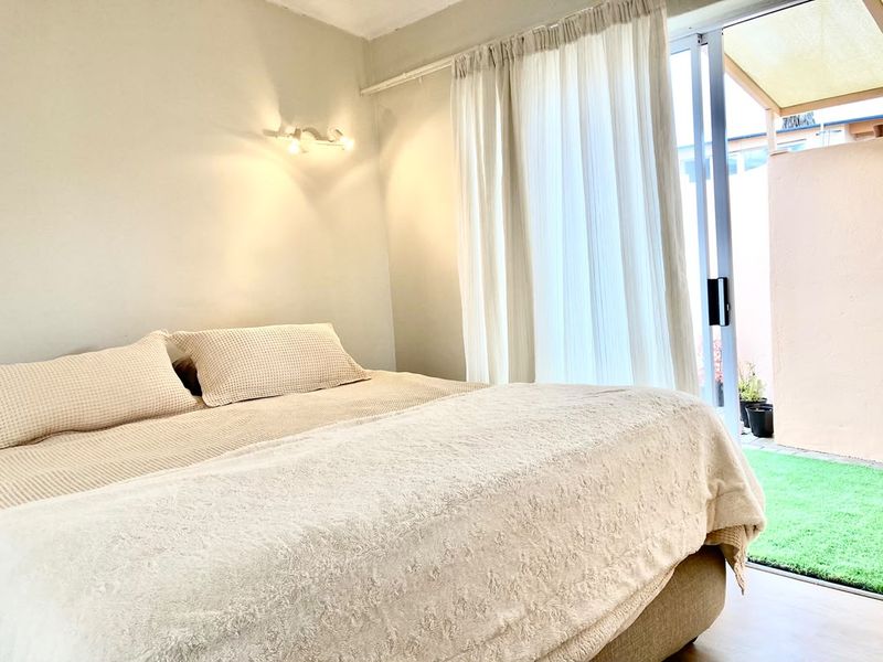 A bright bedroom featuring a sliding glass door that provides direct access to a private outdoor patio area.
