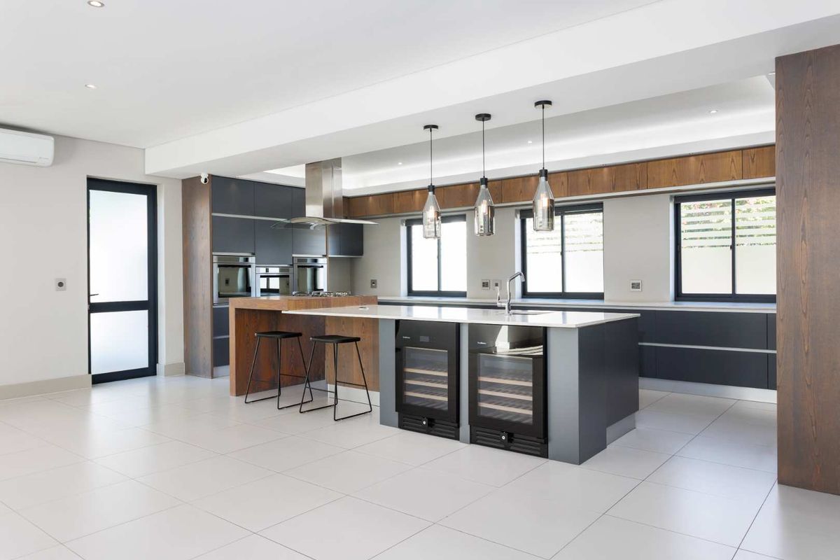 Modern, high-end kitchen featuring a large island with integrated wine coolers, premium cabinetry, built-in appliances, and sleek tiled flooring.